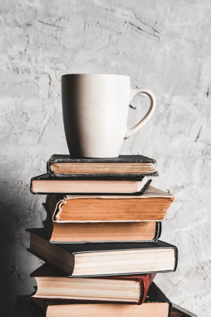 A cup of coffee on of stack of books on grey background. education, study, hobbies, read